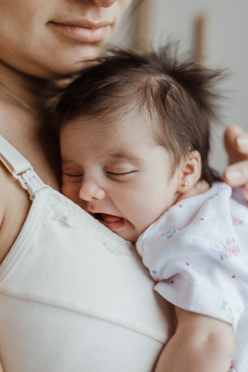 Bebé dormido abrazado a su mamá
